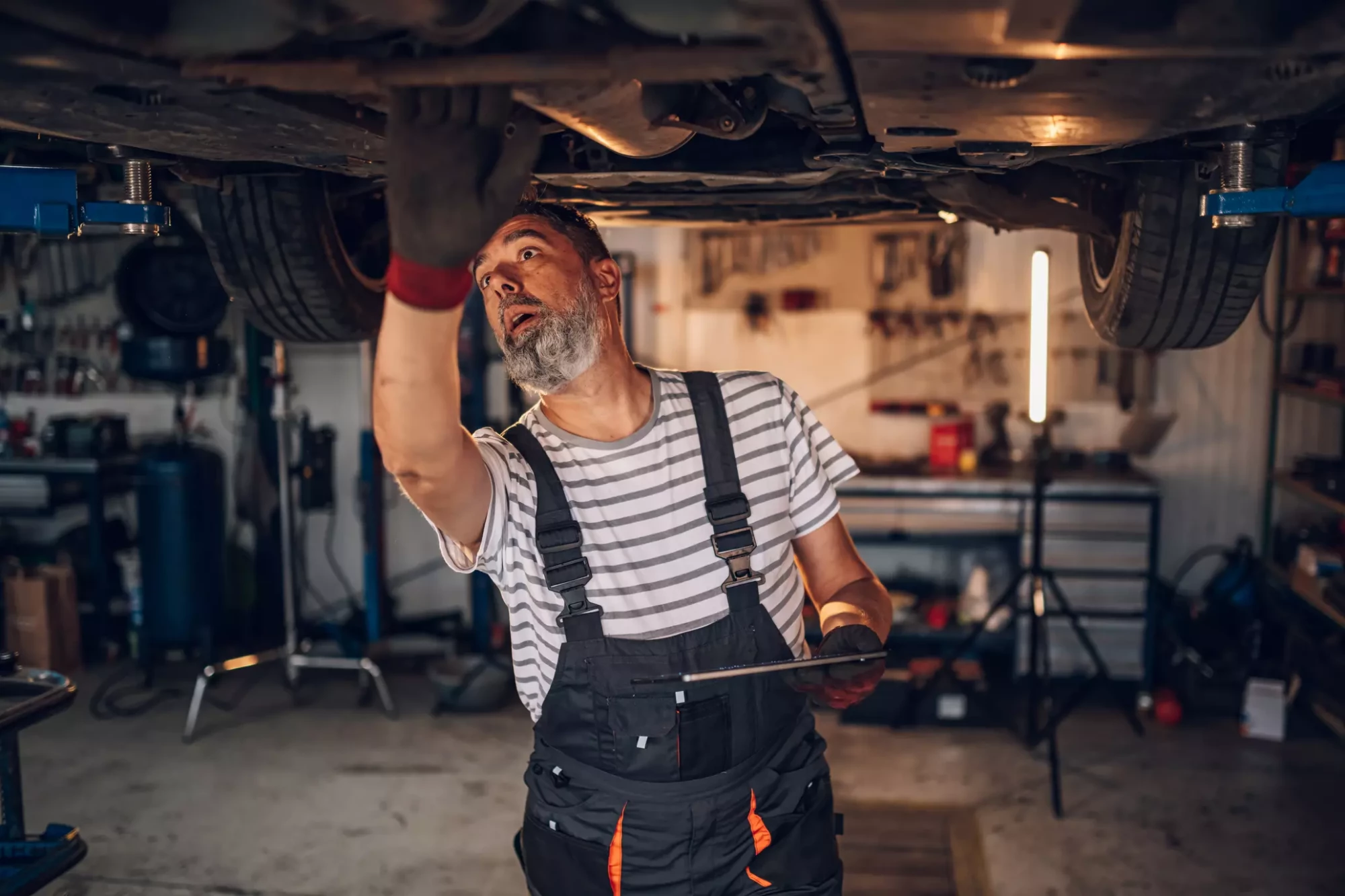 front-view-of-mechanic-under-lifted-car-with-table-2025-04-03-20-04-00-utc